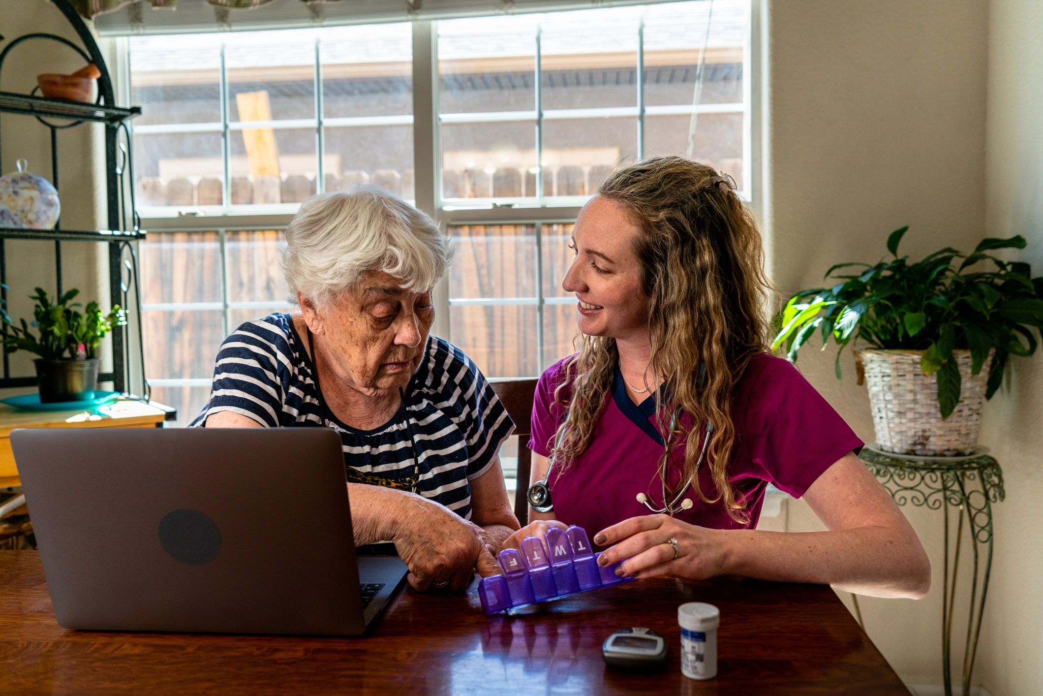 Nurse explaining medications to an older woman at home