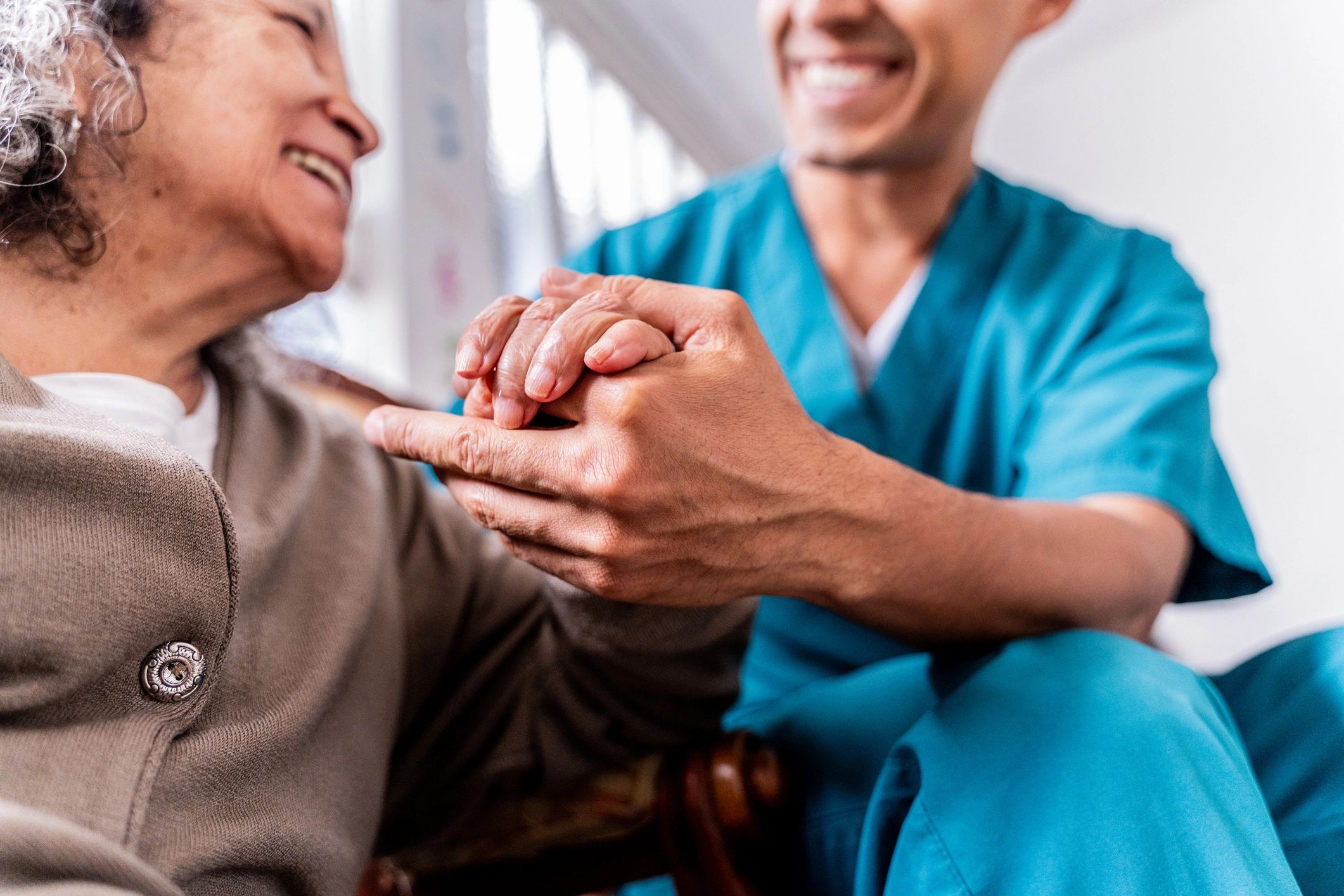 Caregiver holding a senior woman's hands at home